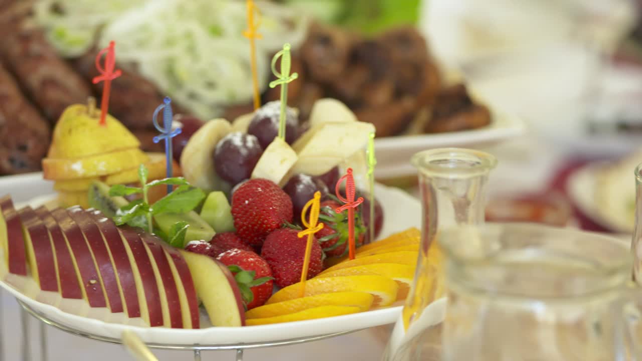 plato de frutas frescas en la mesa de la cena festiva. horquillas de frutas en rodajas variadas