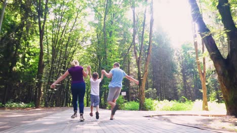 a family of three runs along an alley in the park 01