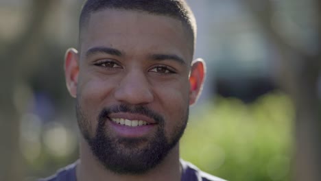 Closeup-of-young-male-face-in-park-looking-at-camera,-smiling