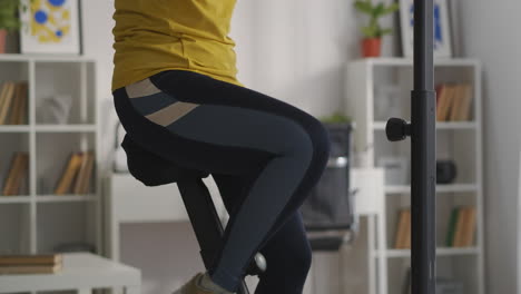 salud y deporte mujer está entrenando en casa usando bicicleta de ejercicio preparando figura y cuerpo hogar fitness equipo deportivo en la sala de estar