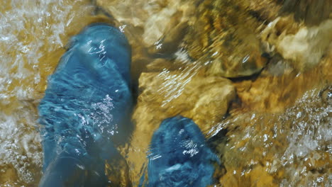 a man in rubber boots stands in the water in a stormy river the top view