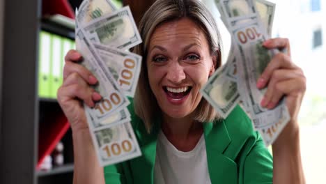 happy woman showing off stacks of us dollar bills