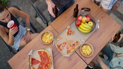 Vista-Superior-De-Una-Compañía-Feliz-Chocando-Vasos-Y-Botellas-Marrones-Durante-El-Inicio-De-Una-Fiesta-En-Una-Mesa-En-El-Patio-De-Una-Casa-De-Campo.