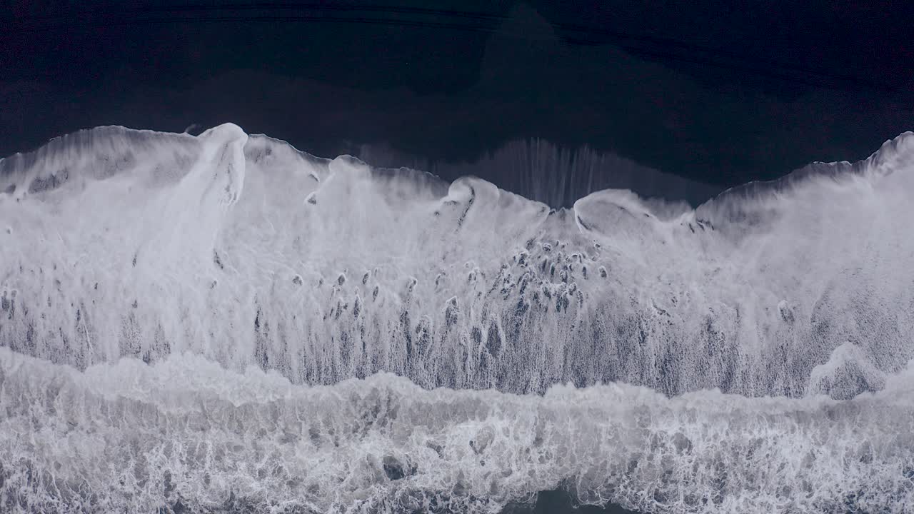 아이슬란드 vi kurfjara의 검은 해변에 도달하는 거대한 파도의 공중 하향식 샷