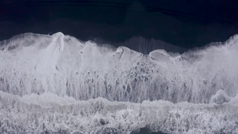 Toma-Aérea-De-Arriba-Hacia-Abajo-De-Olas-Gigantes-Del-Océano-Que-Llegan-A-La-Playa-Negra-De-Vi-Kurfjara,-Islandia