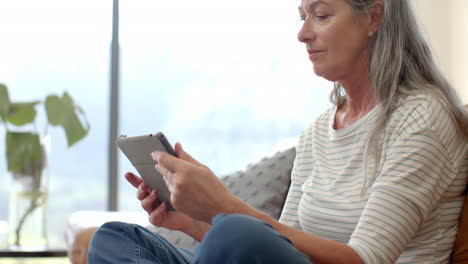 mujer caucásica madura sentada, usando un teléfono inteligente