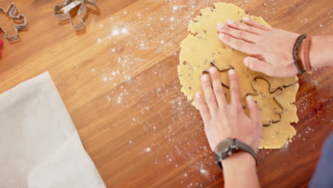 biracial man wearing christmas hat, cutting christmas cookies in kitchen at home, slow motion