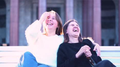 two friends laughing on a park bench