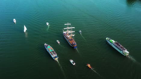 aerial scenic view of a sailing boat escorted with other boats