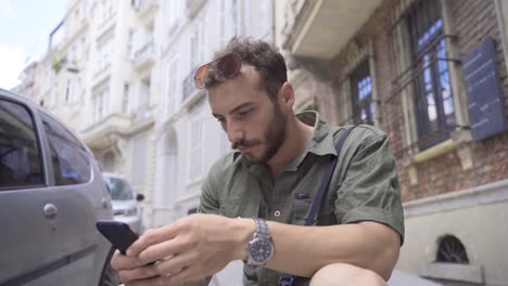 Junger-Mann,-Der-Auf-Der-Straße-Auf-Das-Telefon-Schaut.