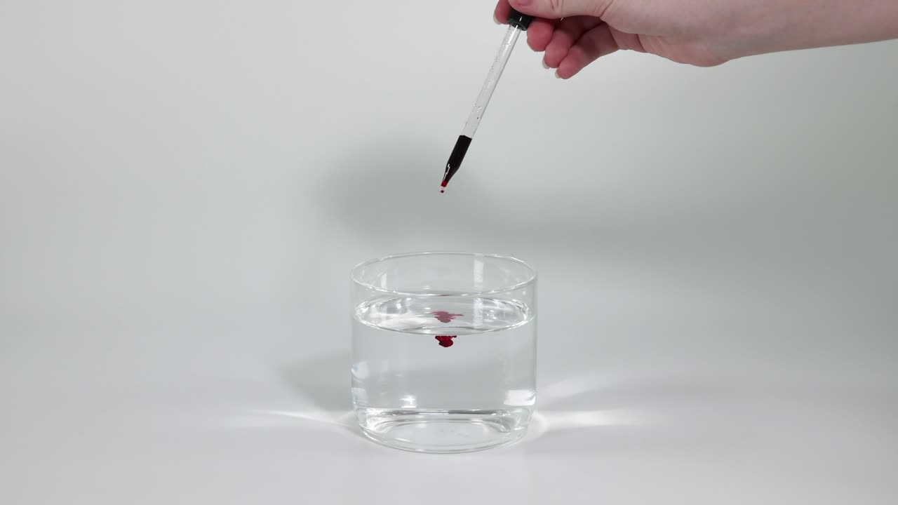 순차적인 잉크 방울이 은 물 잔에 분산됩니다.