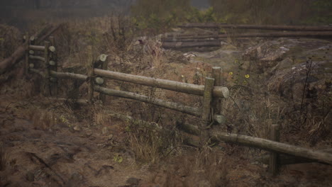 una vieja valla de madera con un campo de campo detrás de ella