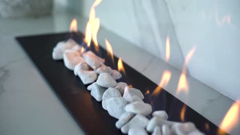 Close-up-tracking-shot-of-indoor-gas-fire-place-with-white-pebbles