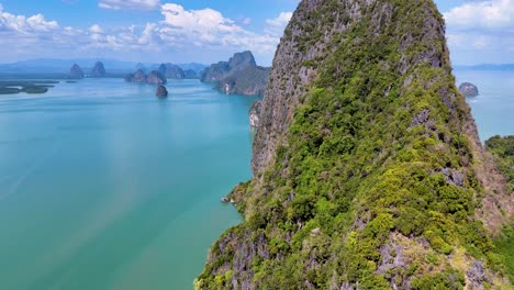 drone footage captures stunning aerial views of phang nga bay's lush cliffs and turquoise waters under bright sunlight