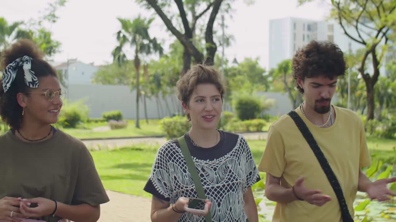 Company of Young Friends Chatting on Walk in Park