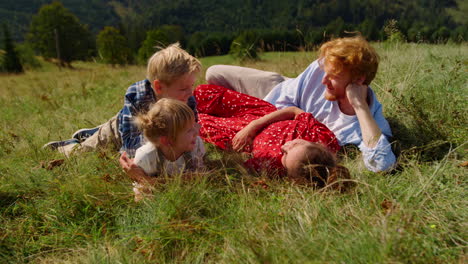 Familia-Tumbada-En-La-Hermosa-Pendiente-De-La-Hierba-Verde.-Padres-Jóvenes-Descansando-Con-Niños.