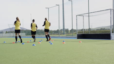 female hockey players practicing drills on field, focusing on teamwork and skills