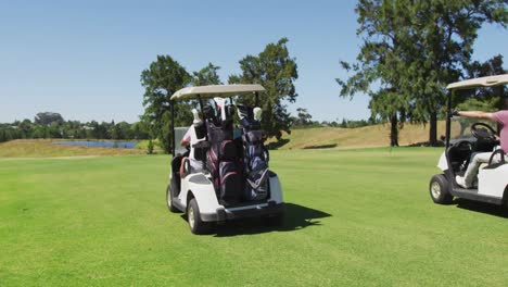 Senior-people-driving-a-golf-cart-with-clubs-on-the-back-at-golf-course