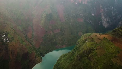 Aerial-shot-flying-over-a-deep-mountainous-valley-with-a-calm-turquoise-river