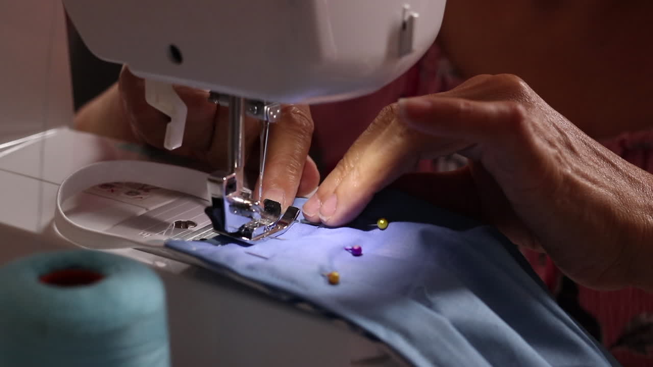 Close Up of Hands Operating a Sewing Machine to Stitch Fabric