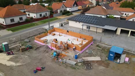 workers building ceramic block wall with tools and equipment on flat foundation