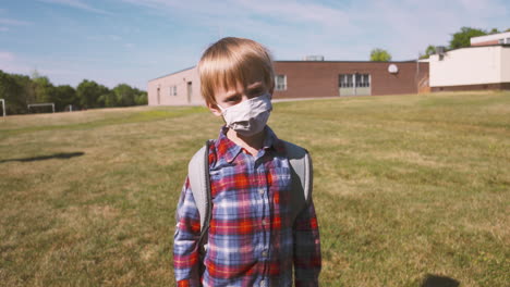 little boy wearing a face mask walking to school