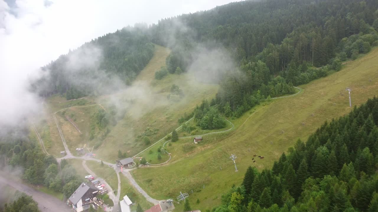 Aerial footage through clouds up a mountain in southern France revealing a alpine roller track. The footage moves forward and rotates slowly to the right to reveal the track through the clouds