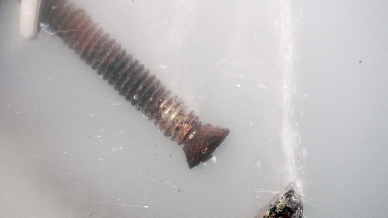 As electric current flows, bubbles form on rusty metal parts during electrolytic cleaning