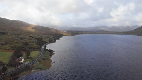 aerial of irish roadway next to kylemore lough and mountain landscape