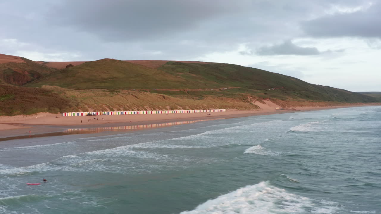 Vista aérea de uma praia arenosa - Surfistas ao pôr do sol durante o verão