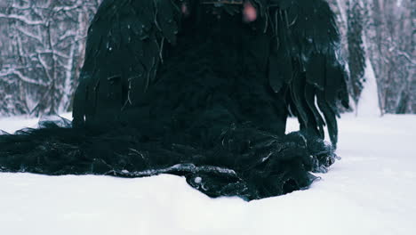 model-in-black-phoenix-costume-walks-through-deep-snowdrift