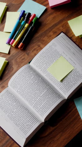 open book with sticky notes and pens on a wooden table
