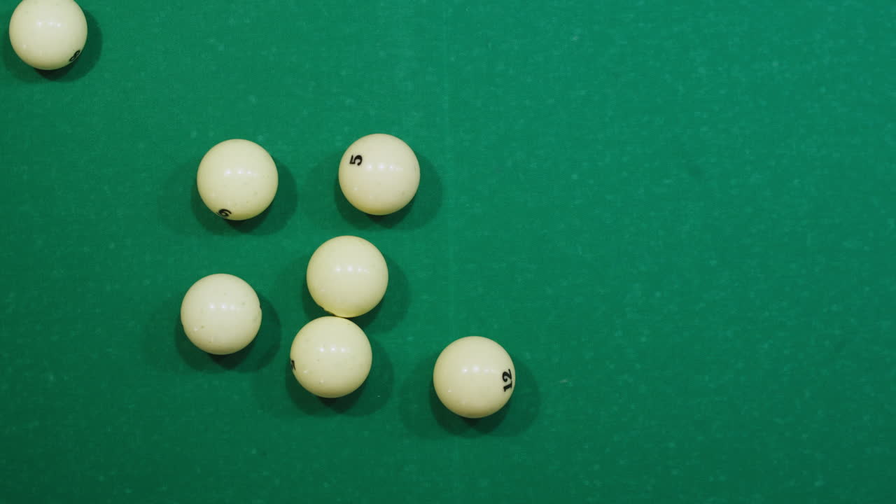 Breaking white pool balls top view on green billiards table for start to play. Russian biliard game, Russian pyramid. Billiard balls with numbers on a pool table. Billiards team sport. High quality 4k footage