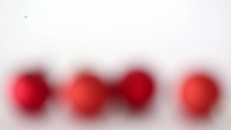 animation of stars over baubles on table against white background