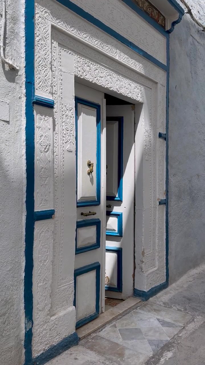 Tunus, Hammamet Medine'sinde dar bir sokakta yarı açık geleneksel beyaz ve mavi oyma kapı.