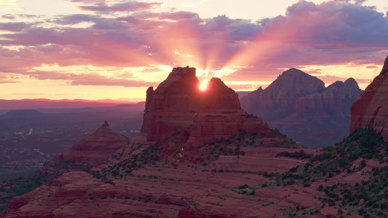 Drone ascends Merry go round rock as last final rays of sunset pierce the sky, backlit in Sedona Arizona