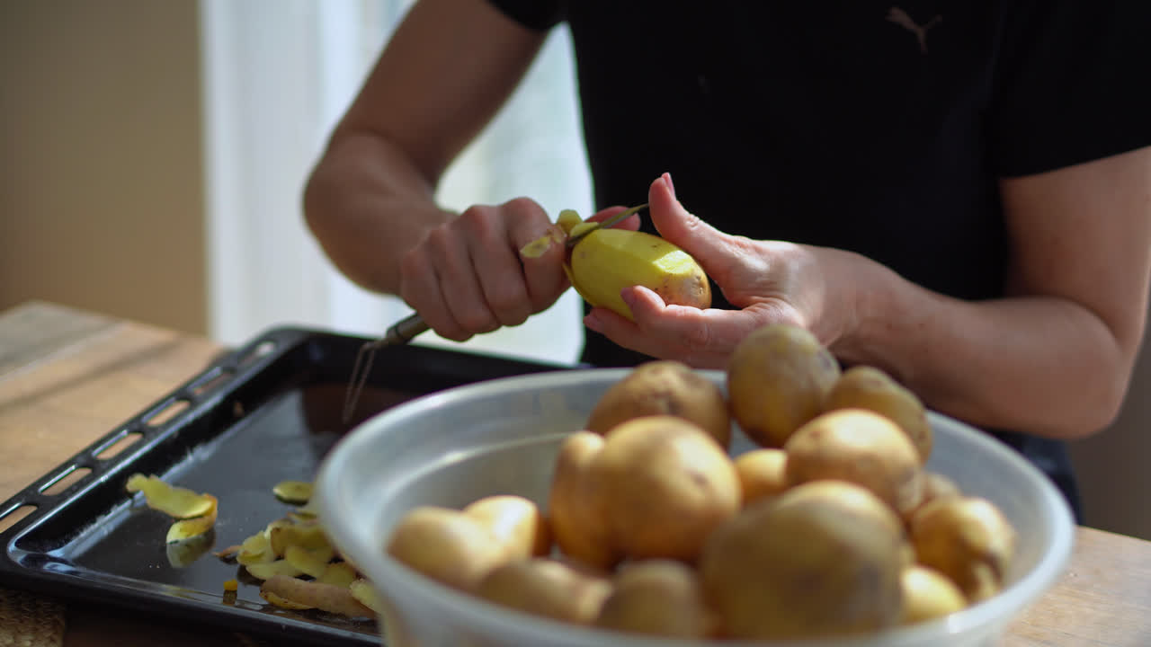 mujer quitando la piel de patatas crudas con un pelador afilado