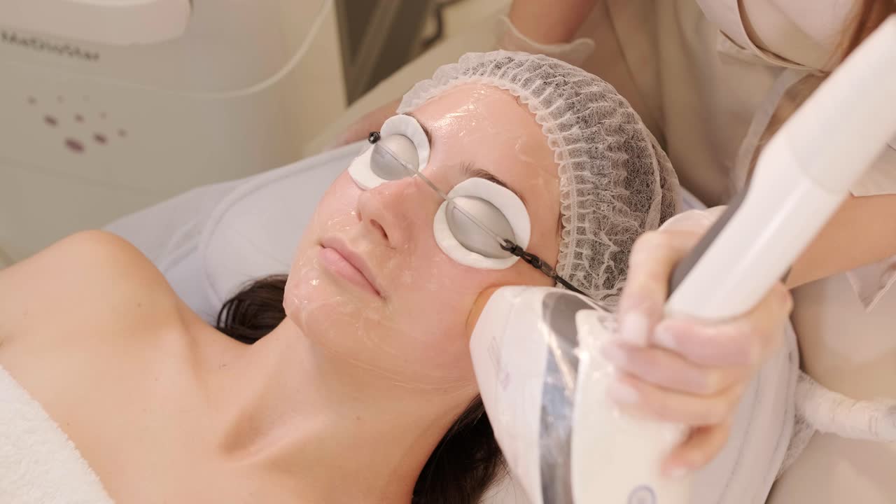 미용 전문가가 얼굴 치료와 얼굴 마스크를 적용합니다.