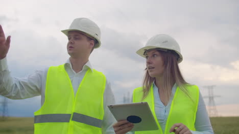 power lines man and woman engineers with a tablet in their hands check the progress of the installation of new towers and analyze the network