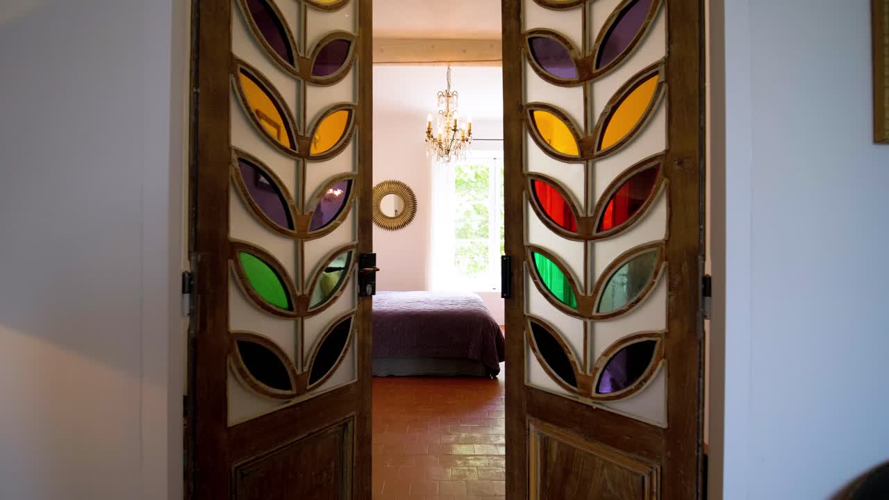 Slow establishing shot of a bedroom with stained glass doors opening