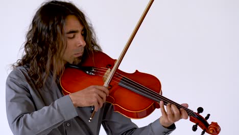 Medium-shot-of-long-hair-ethnic-male-musician-in-grey-button-up-shirt-practicing-music-on-red-viola