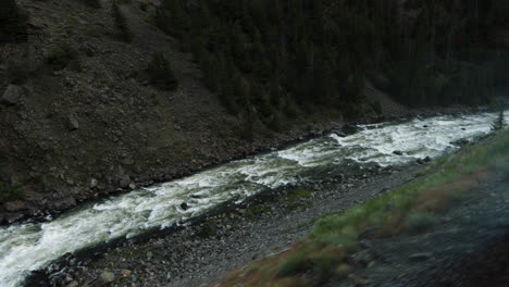 looking down from a cliff onto the raging river while traveling through a mountain pass on a train