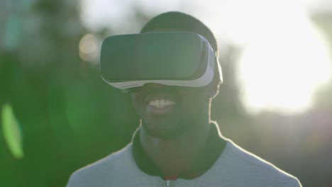 man putting on virtual reality glasses in park, smiling