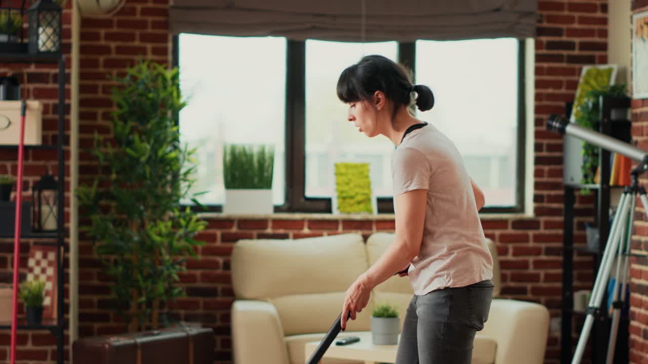 Casual girl using vacuum cleaner to tidy up apartment