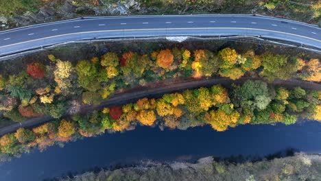 top down aerial of side of mountain with road, railroad track and river