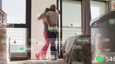 animación de iconos de las redes sociales en pancartas sobre una pareja caucásica enamorada abrazándose en una habitación de hotel