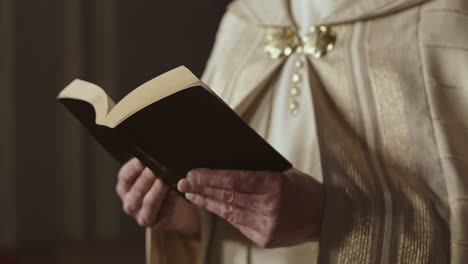 unrecognizable priest reading holy bible
