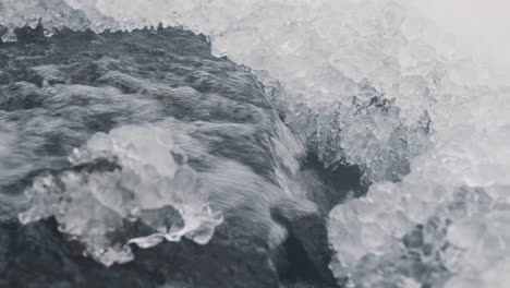 Nahaufnahme-Von-Wasser,-Das-Von-Einem-Kleinen-Wasserfall-In-Einem-Verschneiten-Wald-Fällt-3