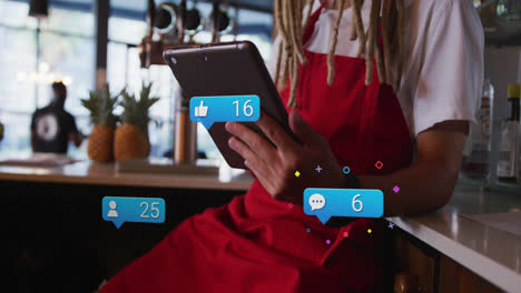 animation of social media icons with numbers over biracial male barista using tablet