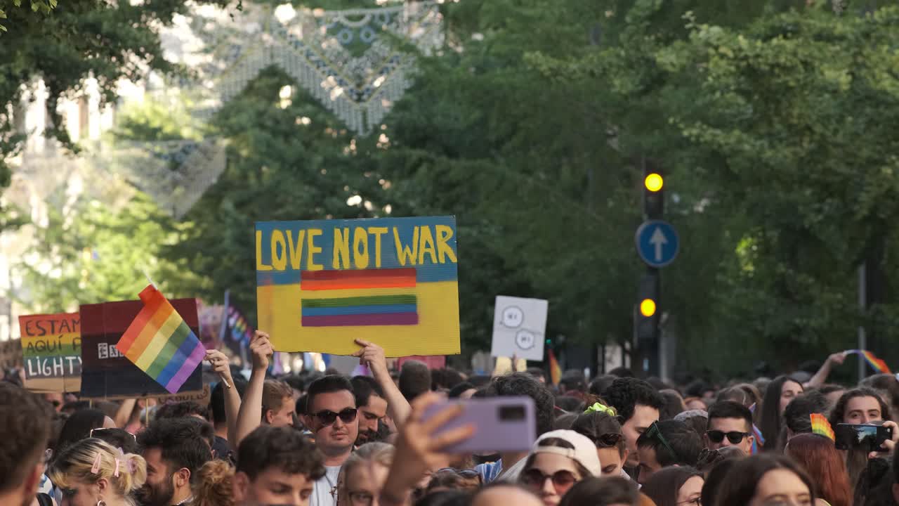 GRANADA, SPAIN - JUNE 28, 2022: People at the pride manifestation, Ukrainian yellow blue flag in hand with text LOVE NOT WAR